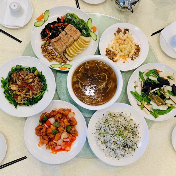 A round table filled with various Chinese dishes, including tofu, vegetables, soup, and rice.