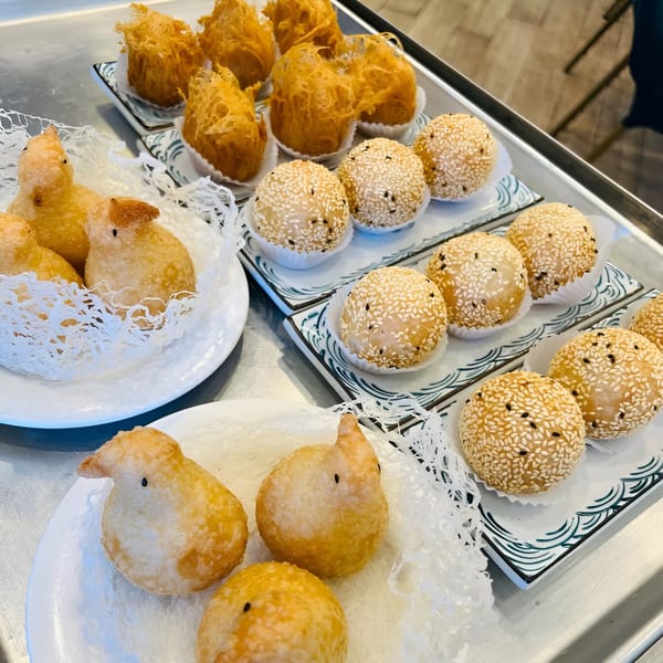 A tray of Imperial Garden dim sum, including bird-shaped pastries, fried taro puffs, and sesame balls.