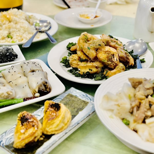 A table laden with various Chinese dishes, including shrimp, fried rice, and dim sum.