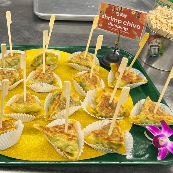 A tray of shrimp chive dumplings, each in a white paper cup with a toothpick.